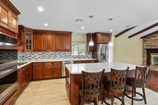 kitchen featuring light countertops, a breakfast bar area, stainless steel appliances, decorative backsplash, and visible vents