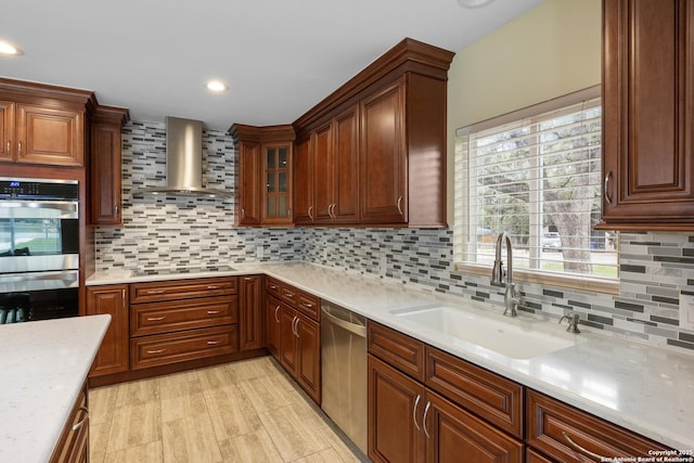 kitchen with wall chimney range hood, decorative backsplash, light countertops, a sink, and stainless steel appliances