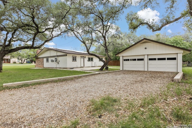 single story home featuring an outbuilding, a front yard, and a detached garage