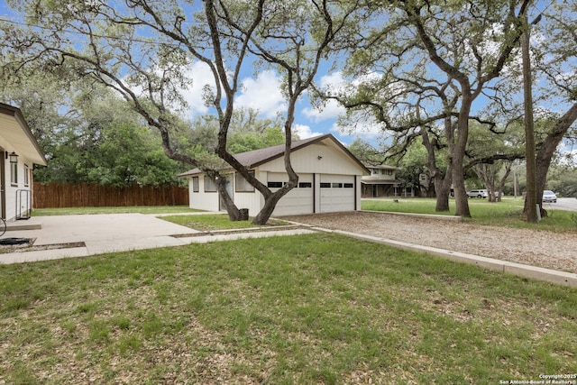 view of front of home featuring fence, an attached garage, a front lawn, an outbuilding, and driveway