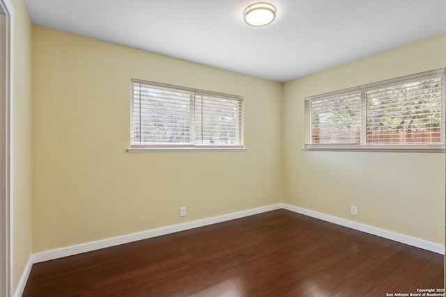 unfurnished room featuring baseboards and dark wood finished floors