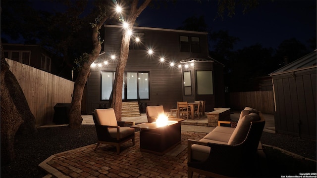 patio at twilight with an outdoor fire pit and fence