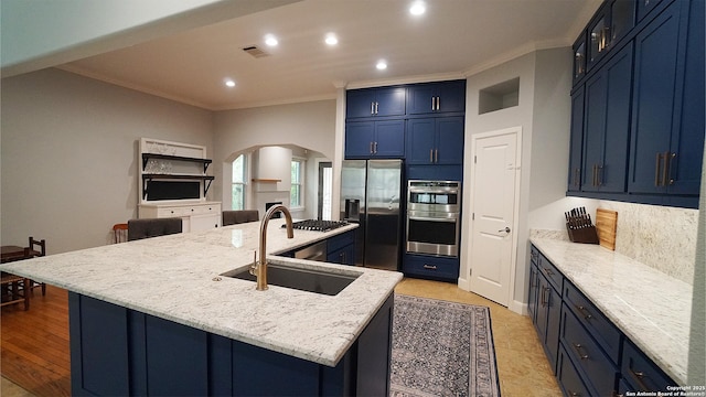 kitchen featuring appliances with stainless steel finishes, a sink, arched walkways, ornamental molding, and blue cabinets