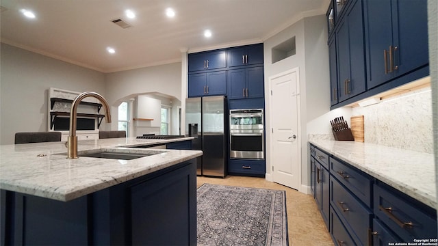 kitchen with arched walkways, blue cabinetry, stainless steel appliances, visible vents, and ornamental molding