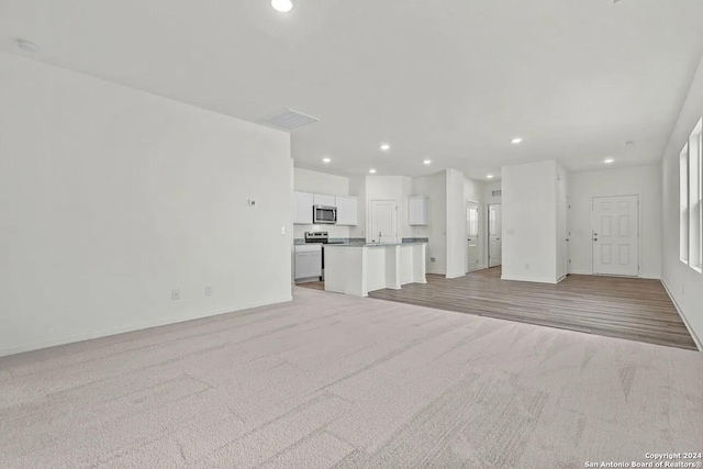 unfurnished living room featuring recessed lighting, baseboards, and light colored carpet