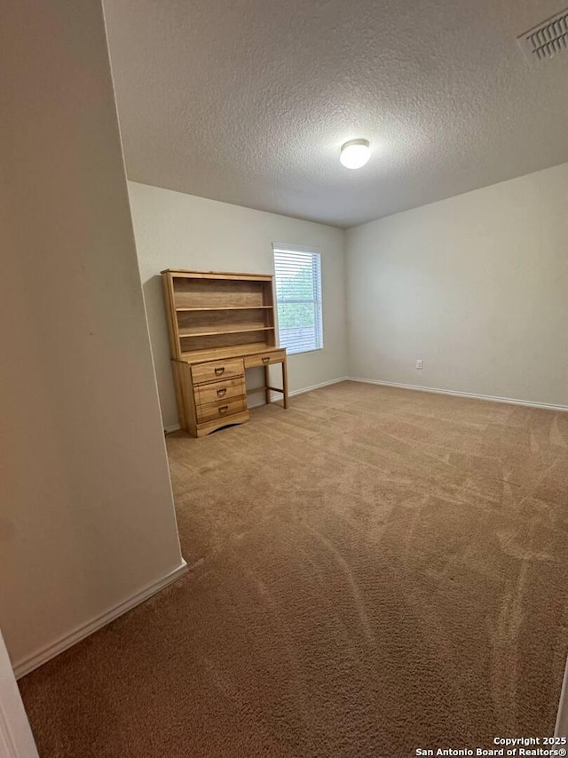 empty room featuring baseboards, a textured ceiling, visible vents, and light carpet