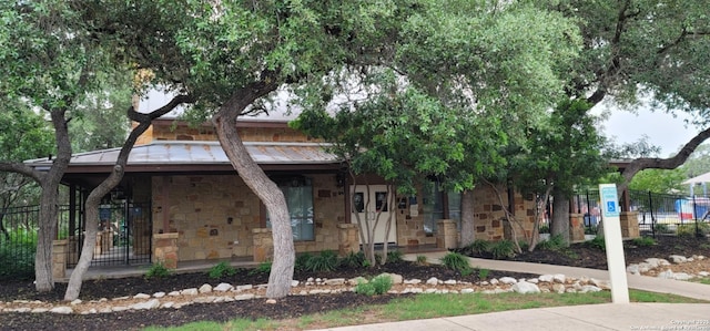 12518 Crockett Way, San Antonio, TX 78253 - view of property hidden behind natural elements featuring covered porch, a standing seam roof, metal roof, fence, and stone siding
