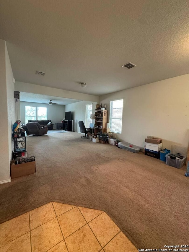 interior space with a healthy amount of sunlight, light carpet, a textured ceiling, and visible vents