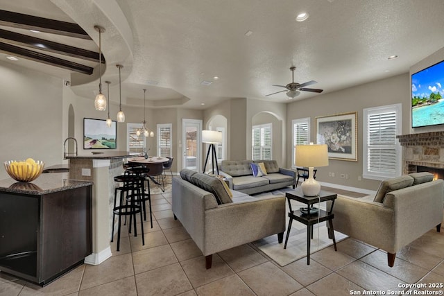 living room featuring arched walkways, recessed lighting, and ceiling fan with notable chandelier