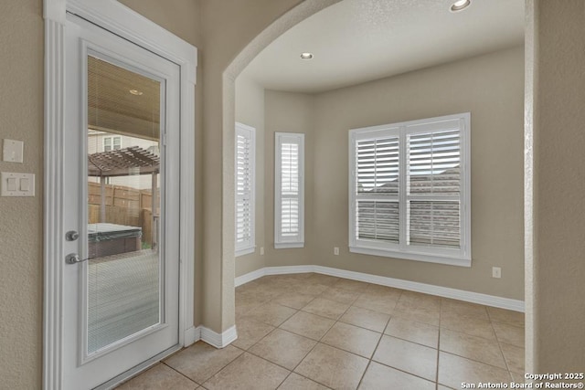 interior space with light tile patterned floors, arched walkways, baseboards, and recessed lighting