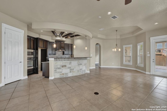 interior space featuring arched walkways, light tile patterned floors, baseboards, a raised ceiling, and ceiling fan with notable chandelier