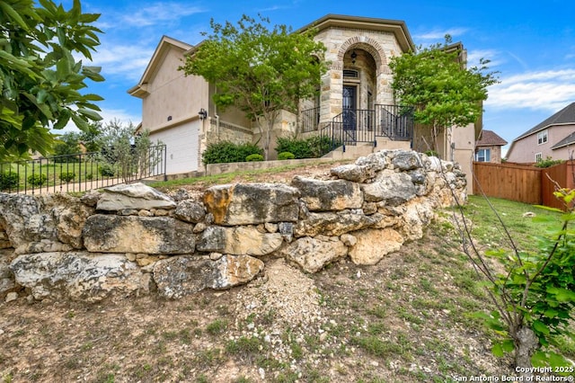view of front of property featuring fence, stone siding, and a garage