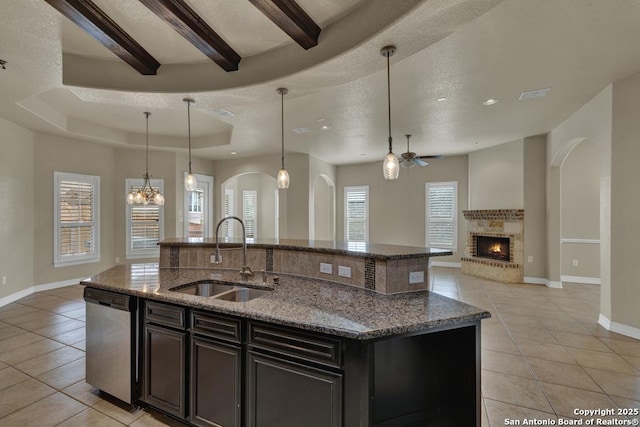 kitchen featuring stainless steel dishwasher, a ceiling fan, baseboards, a sink, and light tile patterned floors