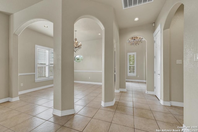 entryway featuring light tile patterned floors, a wealth of natural light, a notable chandelier, and visible vents