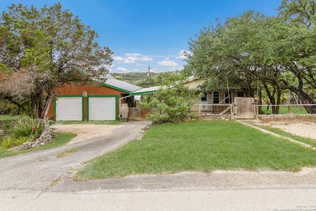 view of front facade with fence, a garage, dirt driveway, a gate, and covered porch