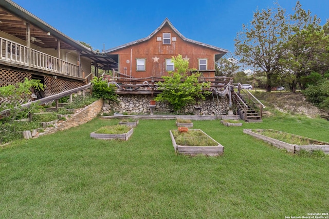 view of yard featuring a wooden deck, a vegetable garden, and stairway