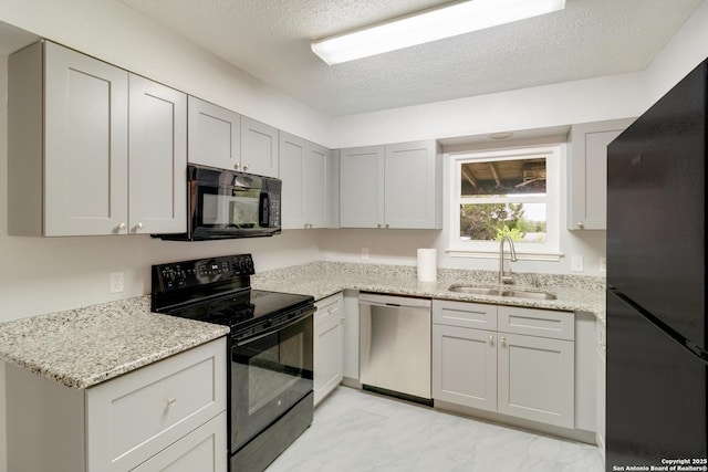 kitchen with a sink, a textured ceiling, black appliances, and light stone countertops