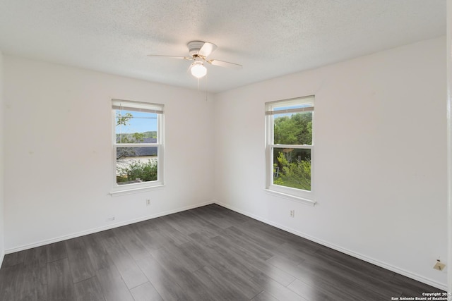 empty room featuring a ceiling fan, a textured ceiling, dark wood-style floors, and a healthy amount of sunlight