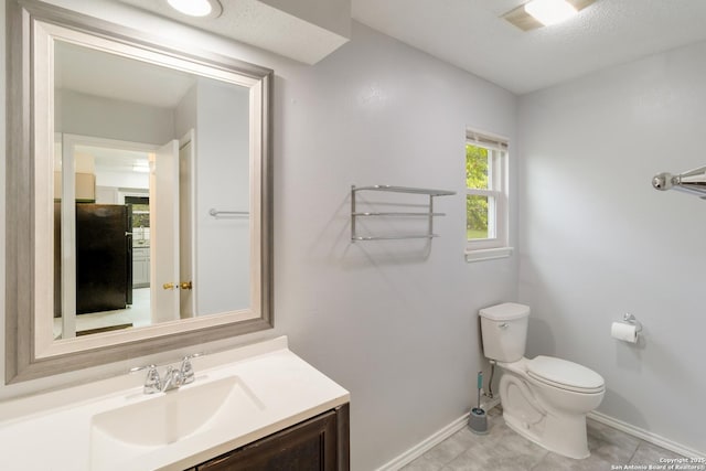 half bath featuring baseboards, tile patterned flooring, vanity, and toilet