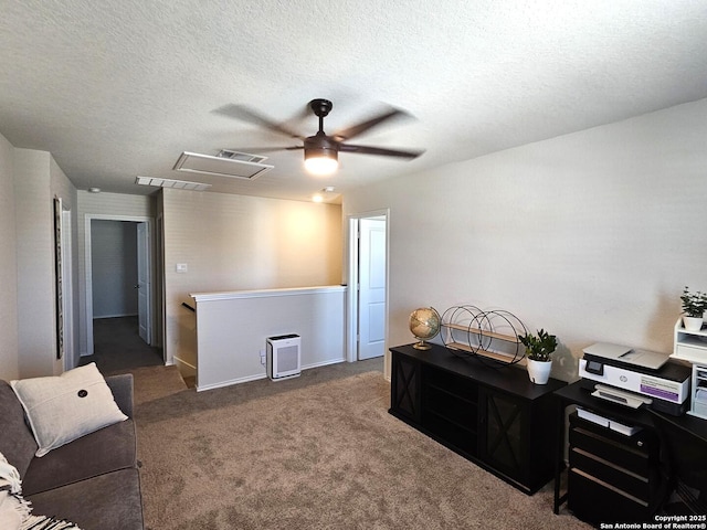 home office featuring a textured ceiling, attic access, carpet, a ceiling fan, and visible vents