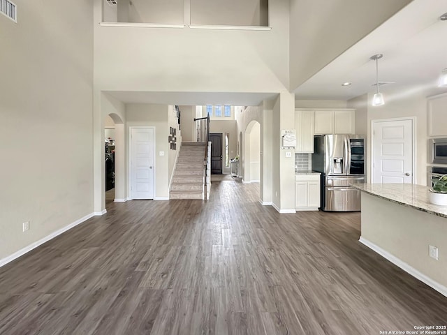 104 Talavera, Boerne, TX 78006 - kitchen featuring appliances with stainless steel finishes, arched walkways, open floor plan, a towering ceiling, and dark wood finished floors