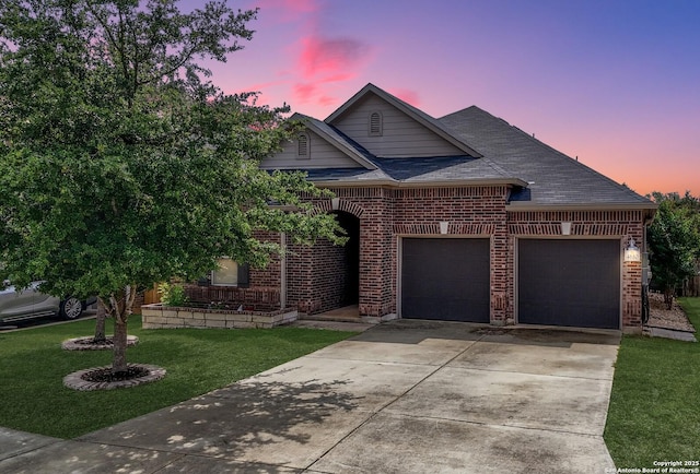 traditional-style house with a lawn, an attached garage, driveway, and brick siding