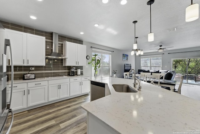 kitchen featuring appliances with stainless steel finishes, a sink, plenty of natural light, wall chimney exhaust hood, and visible vents