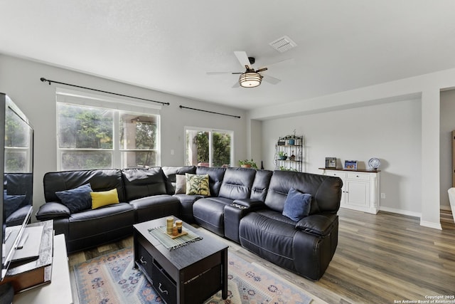 living area featuring baseboards, ceiling fan, visible vents, and wood finished floors