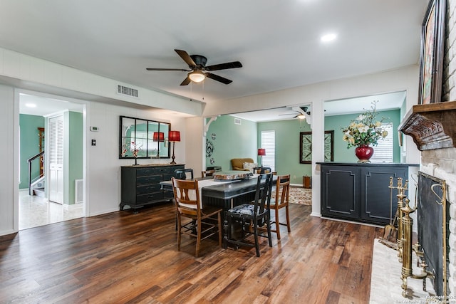dining space with ceiling fan, visible vents, wood finished floors, and a fireplace