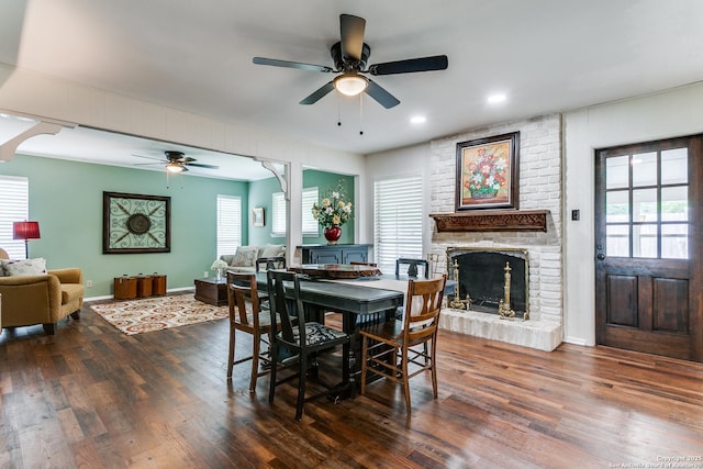 dining space featuring a ceiling fan, wood finished floors, a healthy amount of sunlight, and a fireplace