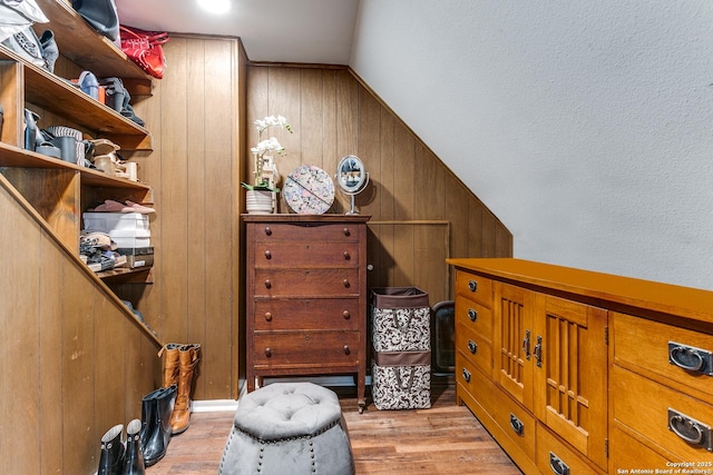 bedroom with light wood-style flooring and wooden walls