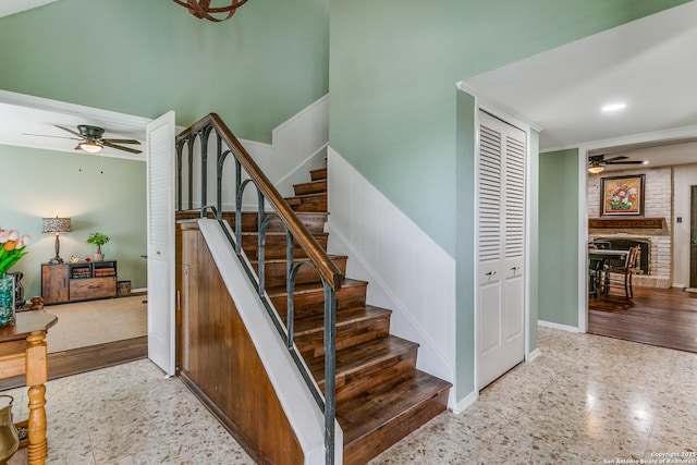 stairs featuring baseboards, a ceiling fan, and a brick fireplace