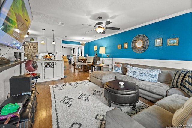 6377 County Road 659, Brazoria, TX 77422 - living area with ceiling fan, a wainscoted wall, wood finished floors, visible vents, and ornamental molding