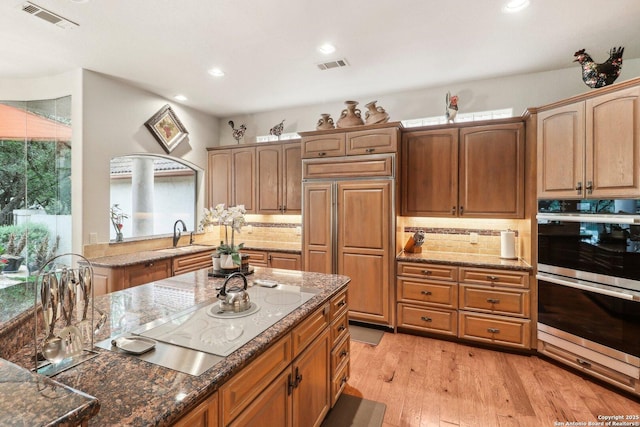 kitchen featuring stainless steel double oven, visible vents, a sink, and white electric stovetop