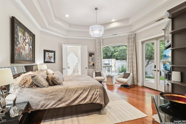 bedroom with access to exterior, wood finished floors, an inviting chandelier, a tray ceiling, and recessed lighting