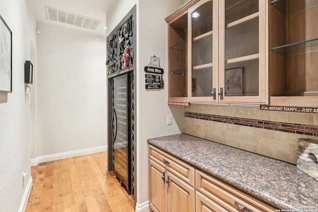 bar featuring visible vents, decorative backsplash, light wood-style floors, baseboards, and beverage cooler