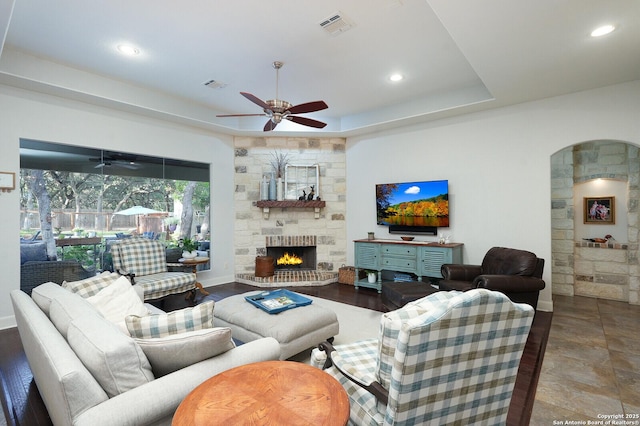213 Heavens Way, San Antonio, TX 78260 - living room featuring ceiling fan, a raised ceiling, arched walkways, a stone fireplace, and visible vents
