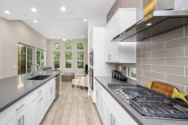 440 E Olmos, San Antonio, TX 78212 - kitchen with wall chimney range hood, stainless steel appliances, a sink, white cabinetry, and recessed lighting