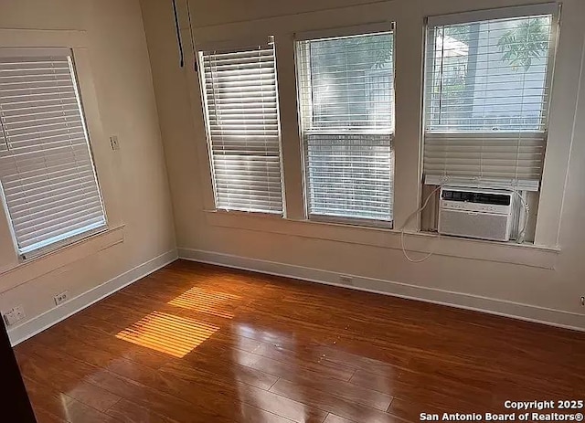 spare room featuring baseboards, wood finished floors, and cooling unit