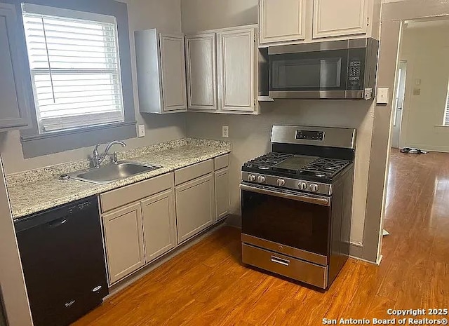 kitchen with white cabinets, stainless steel appliances, a sink, and light wood-type flooring