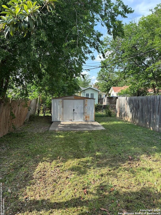 view of yard featuring a storage shed, an outbuilding, and a fenced backyard