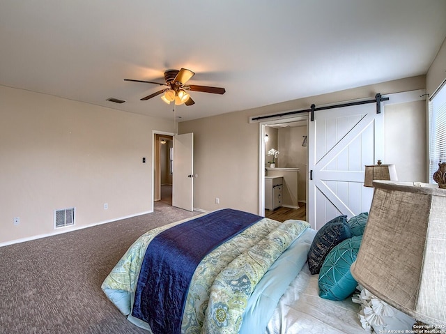 carpeted bedroom with visible vents, a barn door, baseboards, and ceiling fan
