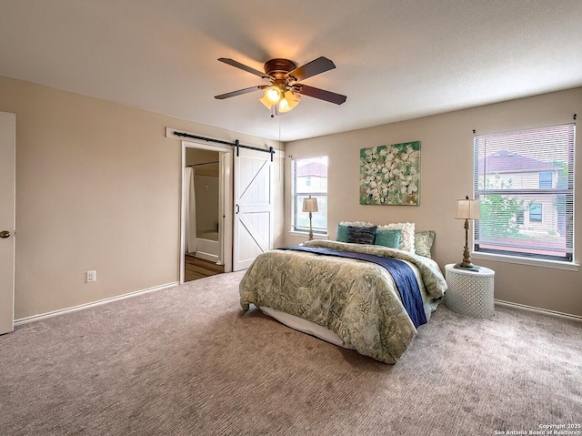 bedroom with ceiling fan, a barn door, carpet, baseboards, and ensuite bathroom