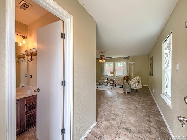 hallway with baseboards, visible vents, and tile patterned floors