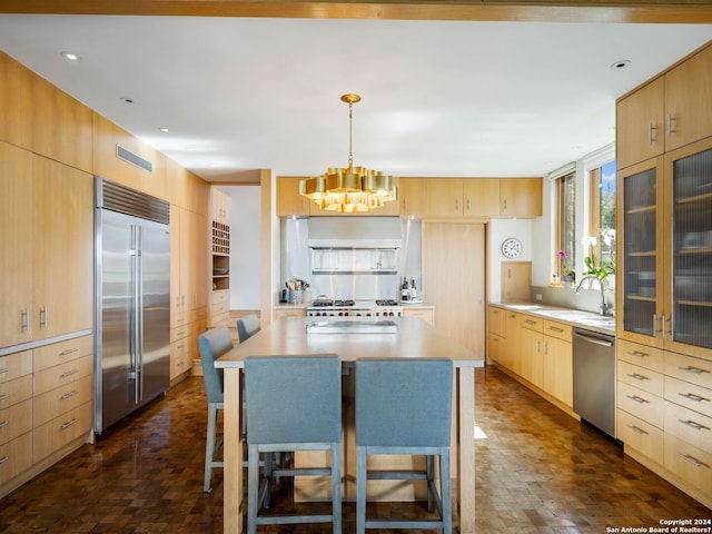 kitchen with light brown cabinetry, appliances with stainless steel finishes, a sink, light countertops, and an inviting chandelier