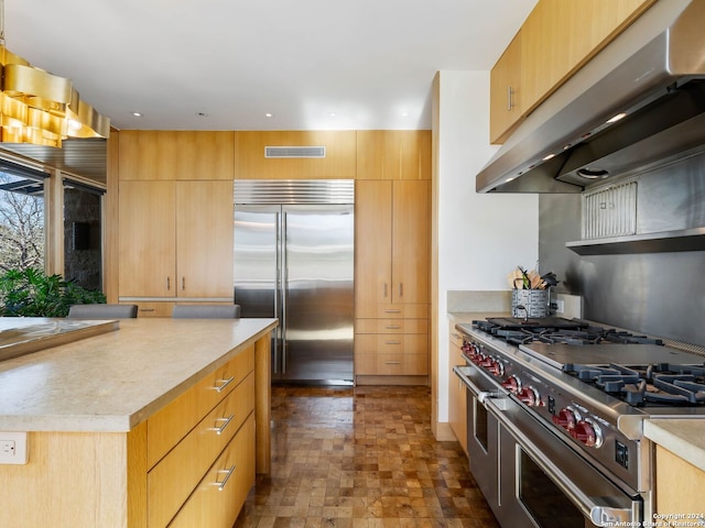 kitchen with high quality appliances, light countertops, under cabinet range hood, visible vents, and modern cabinets