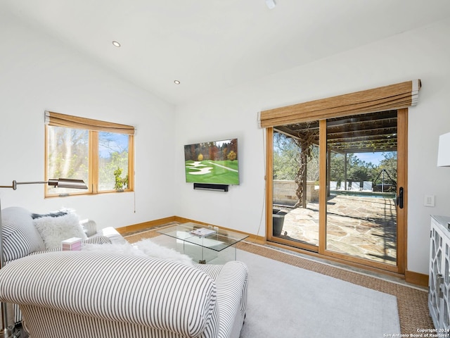 carpeted living room featuring baseboards, vaulted ceiling, and a wealth of natural light