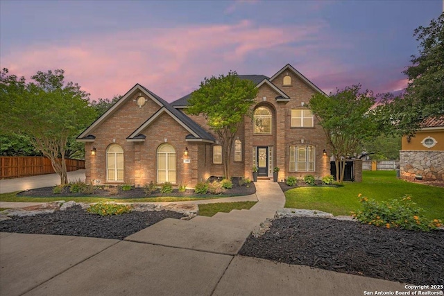 traditional-style house with brick siding, fence, and a front yard