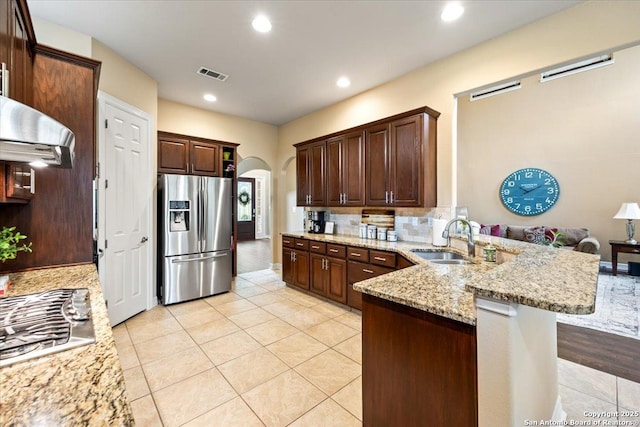 kitchen with a sink, arched walkways, stainless steel appliances, a peninsula, and visible vents