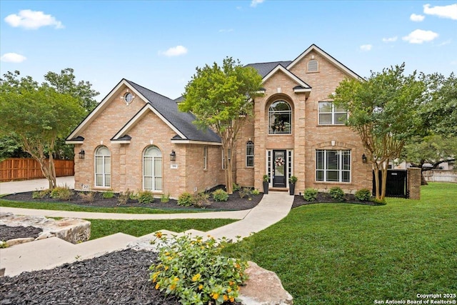 traditional home featuring brick siding, a front lawn, and fence